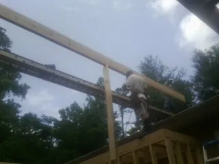 Carpenter setting a ridge beam over a new addition frame — Ice Dam Removal by Roofing Brothers in Lismore