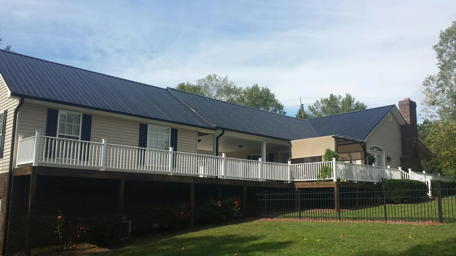 Black metal roof above a long white railed deck on a hillside home in Lismore