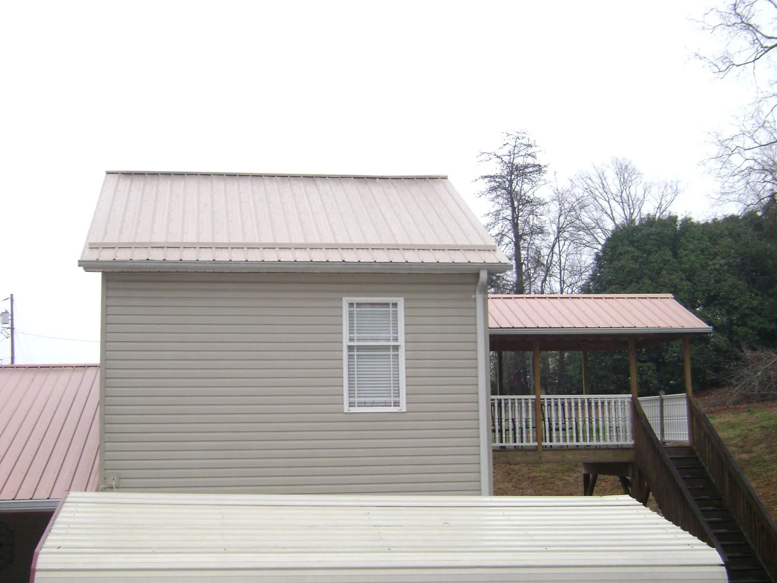 Tan metal roofs on a two story addition and attached porch, from a Roof Replacement job in Lismore