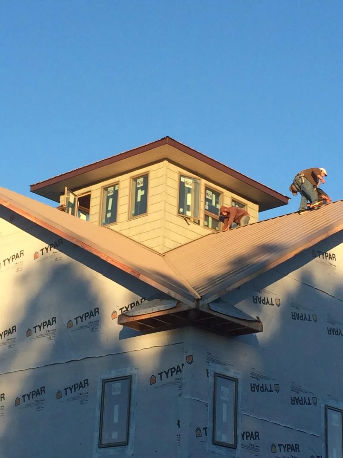 Roofers working around a rooftop cupola on a new metal roof at sunset — Roof Waterproofing in Lismore by Roofing Brothers